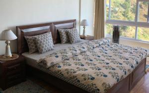 a bed in a bedroom with two lamps and a window at Vilasa by StayApart x Merlot Pines in Kasauli