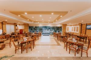 um restaurante vazio com mesas e cadeiras de madeira em Arion Suites Hotel em Bandung