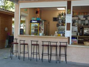 um bar com quatro bancos em frente a uma loja em CAMPING LE NAVARRE *** em Vias