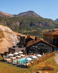 a resort with a pool with umbrellas and a building at Fýri Resort in Hemsedal