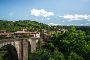 eine alte Steinbrücke über eine Stadt mit Bäumen in der Unterkunft Les Sources Gite Cabernet in Chambonas