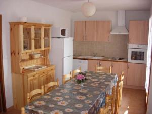 eine Küche mit einem Tisch mit Stühlen und einem weißen Kühlschrank in der Unterkunft Les Sources Gîte Sauvignon in Chambonas