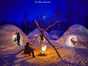 a group of people sitting around a fire in an igloo at 真狩村焚き火キャンプ場 in Makkari