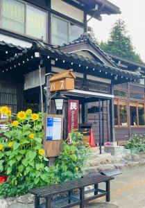 un banco frente a un edificio con un cartel en Minsyuku Koshiyama, en Shirakawa