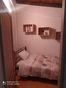 Habitación pequeña con cama y estanterías en la pared en Casa del Sol en Arónion