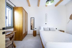 ein Schlafzimmer mit einem weißen Bett und einem Fenster in der Unterkunft ANGONI SUITES in Kardamaina