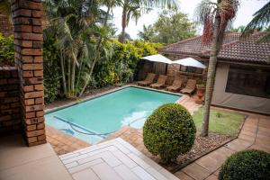 a swimming pool in a yard with chairs and a house at White River Country Estate - Self Catering - AMH Home in White River