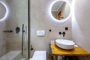 ein Bad mit einem Waschbecken, einer Dusche und einem Spiegel in der Unterkunft ANGONI SUITES in Kardamaina