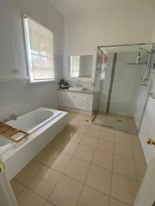 a white bathroom with a tub and a shower at The Sugarloaf Homestead in Kyoomba