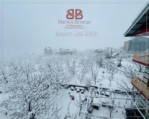 een met sneeuw bedekt veld met bomen en gebouwen bij Burwa Breeze By Winsum Stays in Palchān