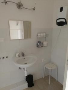 - une salle de bains blanche pourvue d'un lavabo et d'un tabouret dans l'établissement Zsuzsanna Vendégház, à Gyomaendrőd