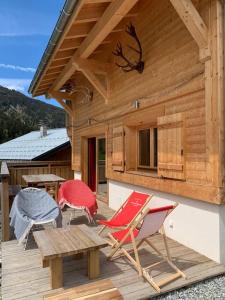 a wooden deck with chairs and a table and a building at Individual chalet for up to 12 people maximum in Les Contamines-Montjoie