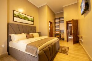 - une chambre avec un grand lit et une télévision à écran plat dans l'établissement INGANZO BOUTIQUE HOTEL, à Kigali