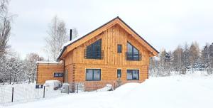 una casa in legno nella neve con una recinzione di wellness roubenka Holčí a Miřetice