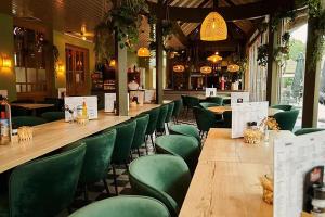 un restaurant avec des chaises vertes et un long bar dans l'établissement Camping Marvilla Parks Kaatsheuvel - Roan, à Kaatsheuvel