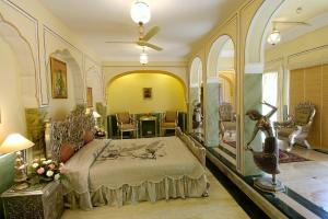 a bedroom with a bed and a table and chairs at The Raj Palace (Small Luxury Hotels of the World) in Jaipur