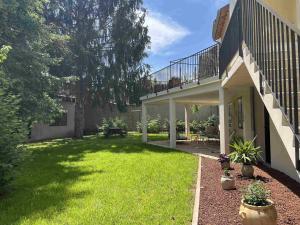 a backyard of a house with a balcony and grass at Le Jardin du Dolaizon in Le Puy en Velay