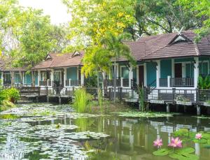 une rangée de maisons avec des nénuphars dans un étang dans l'établissement Le Charme Sukhothai Historical Park - SHA Extra Plus, à Sukhothaï