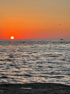 una puesta de sol sobre el océano con un barco en la distancia en ЖК Три короны, en Aktau