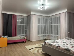 a bedroom with two beds and large windows at ЖК Три короны in Aktau