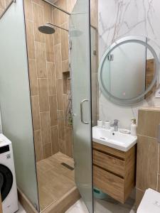 un bagno con doccia, lavandino e specchio di ЖК Три короны ad Aqtau
