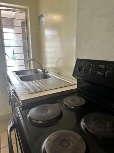 uma cozinha com um lavatório e um fogão forno superior em Stay at Home Airport Lodge em Kempton Park