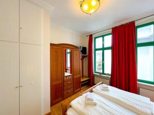 ヘリングスドルフにあるVilla Perkunosのベッドルーム1室(ベッド2台、赤いカーテン付)