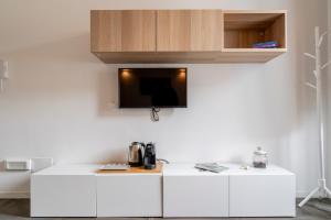 a kitchen with white cabinets and a tv on a wall at SoClà Boutique Hotel RTA in Taranto
