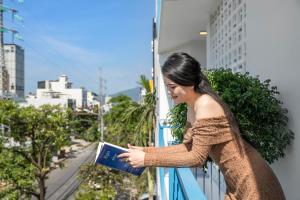 a woman standing on a balcony reading a book at Dana House ELC in Da Nang