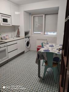 een keuken met een tafel en een wasruimte bij Precioso piso totalmente reformado. in Gijón