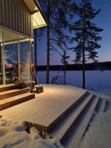 una casa con terraza en la nieve en Ihana järvenranta mökki. Cottage by the lake., en Kurjalanranta