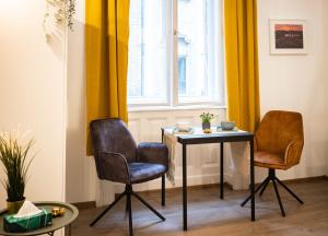 twee stoelen en een tafel in een kamer met gele gordijnen bij Free Parking -Corvin Palace Residence-3BDRM,6ppl,Wifi,AC in Boedapest