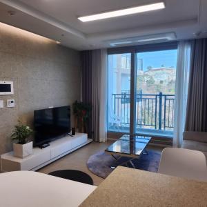 a living room with a tv and a large window at Ungcheon Hotel in Yeosu