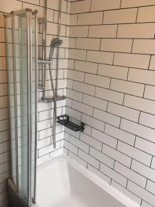 a shower in a white tiled bathroom with a tub at Abingdon Cosy Nest in Sunningwell