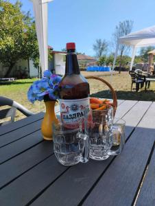 a bottle of beer and some glasses on a table at Kemping pod figą in Granichar