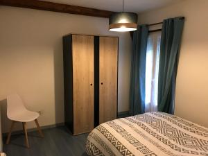 1 dormitorio con 1 cama, armario y silla en Maison region de Domme, en Saint-Martial-de-Nabirat