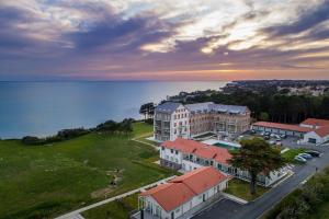 Una vista aérea de un edificio junto al agua. en Appartement pour 4 face mer plage + piscine, en La Birochere