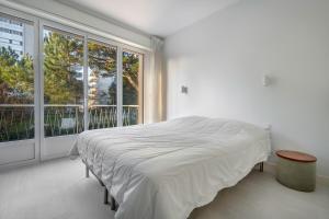 - une chambre blanche avec un lit et une grande fenêtre dans l'établissement Parenthese familiale tout pres de la plage, à Pornichet