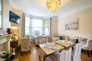 a dining room with tables and chairs and a chandelier at OYO Lina Guest House in Oxford