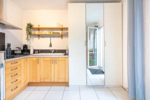 una cocina con armarios de madera y una puerta corredera de cristal en Studio 4 Vercors - Terrasse et parking Privé, en Meylan