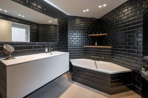 een badkamer met een bad en zwarte bakstenen muren bij Locarno in Knokke-Heist