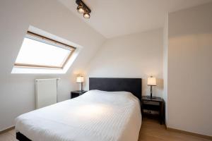 sypialnia z białym łóżkiem i dwoma stołami z lampkami w obiekcie Locarno w mieście Knokke-Heist