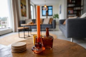 Una vela y una botella sobre una mesa en una sala de estar. en 8 persons waterfront Villa, en Roelofarendsveen