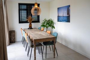 Un comedor con mesa y sillas de madera. en 8 persons waterfront Villa, en Roelofarendsveen