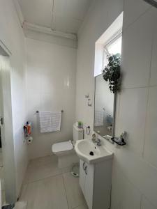 La salle de bains blanche est pourvue d'un lavabo et de toilettes. dans l'établissement A Cheerful Furnished Bedroom Retreat, à Johannesbourg