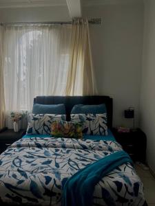 - un lit avec des draps bleus et blancs et une fenêtre dans l'établissement A Cheerful Furnished Bedroom Retreat, à Johannesbourg