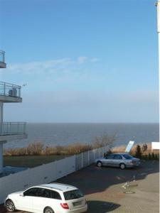 zwei Autos auf einem Parkplatz neben dem Meer geparkt in der Unterkunft Seehütte Ferienwohnung 104 in Cuxhaven