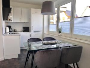 cocina y comedor con mesa de cristal y sillas en Villa Döser Strand, en Cuxhaven