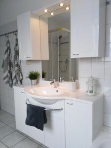 a white bathroom with a sink and a mirror at Villa Döser Strand in Cuxhaven