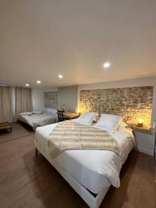 a bedroom with a large bed and a stone wall at Superbe appartement avec spa privatif in Vincelles